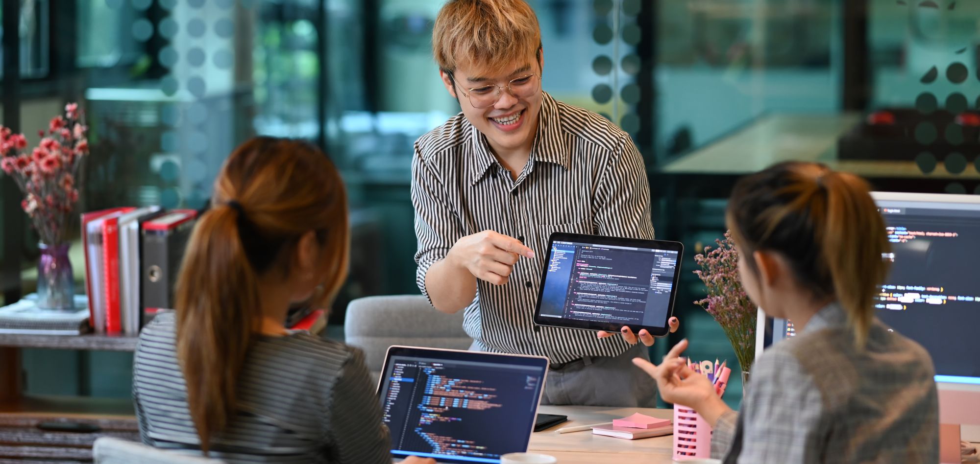 A developer presents code to two interns