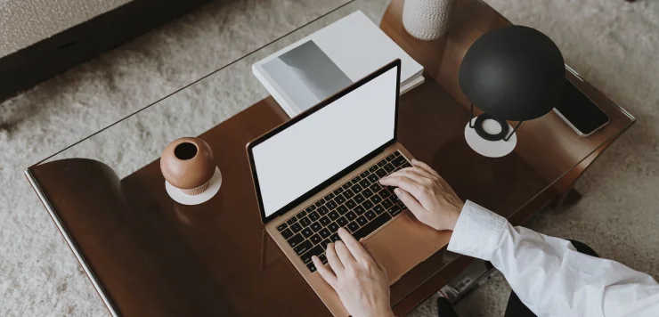 A blank laptop is shown on a wood table