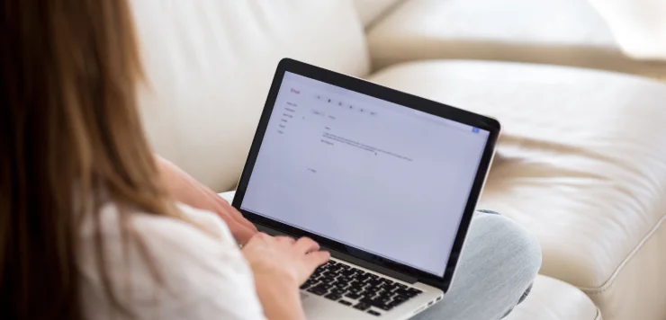 A copywriter types an email on her laptop