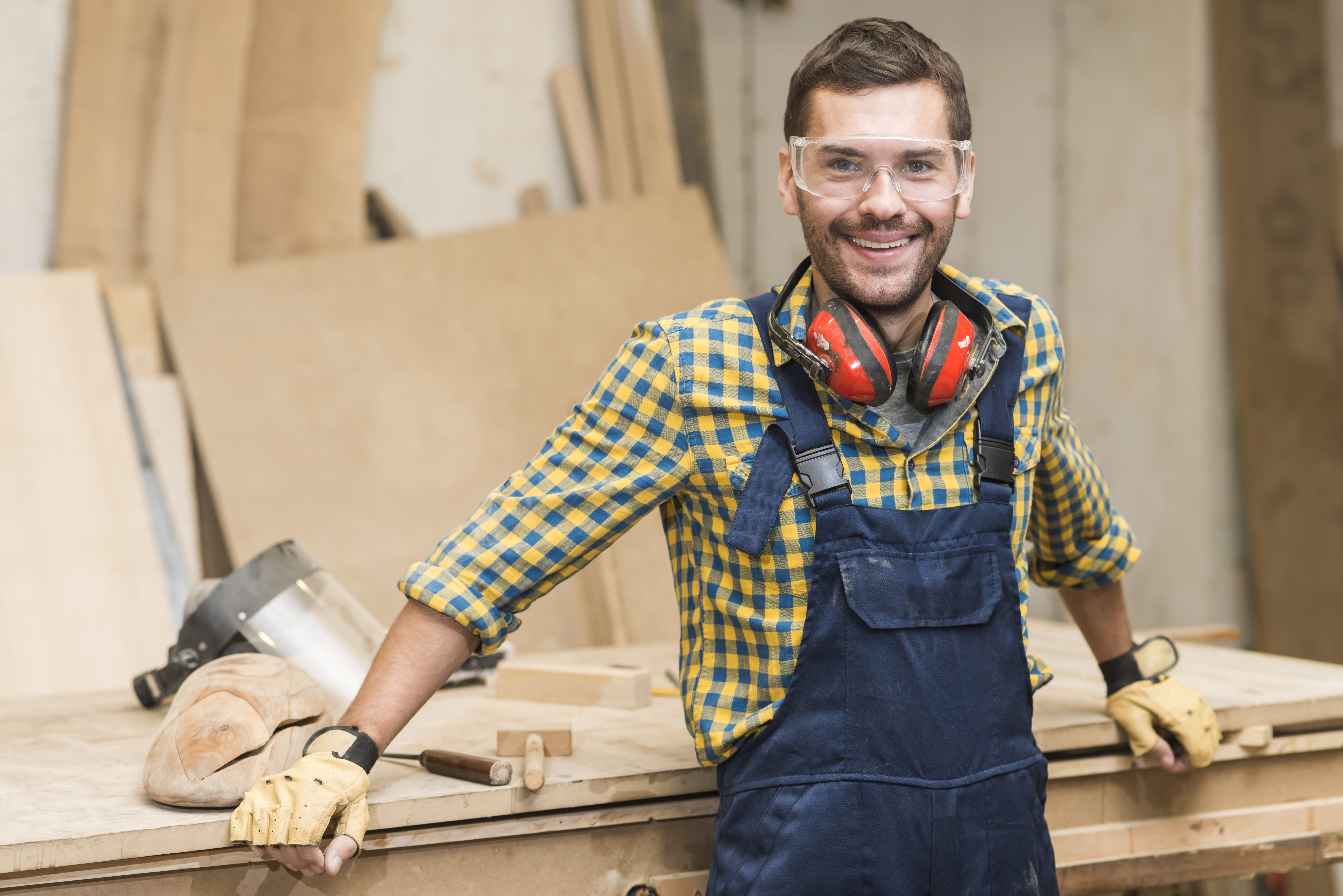 Smiling tradesman looking towards a camera while by a workbench.